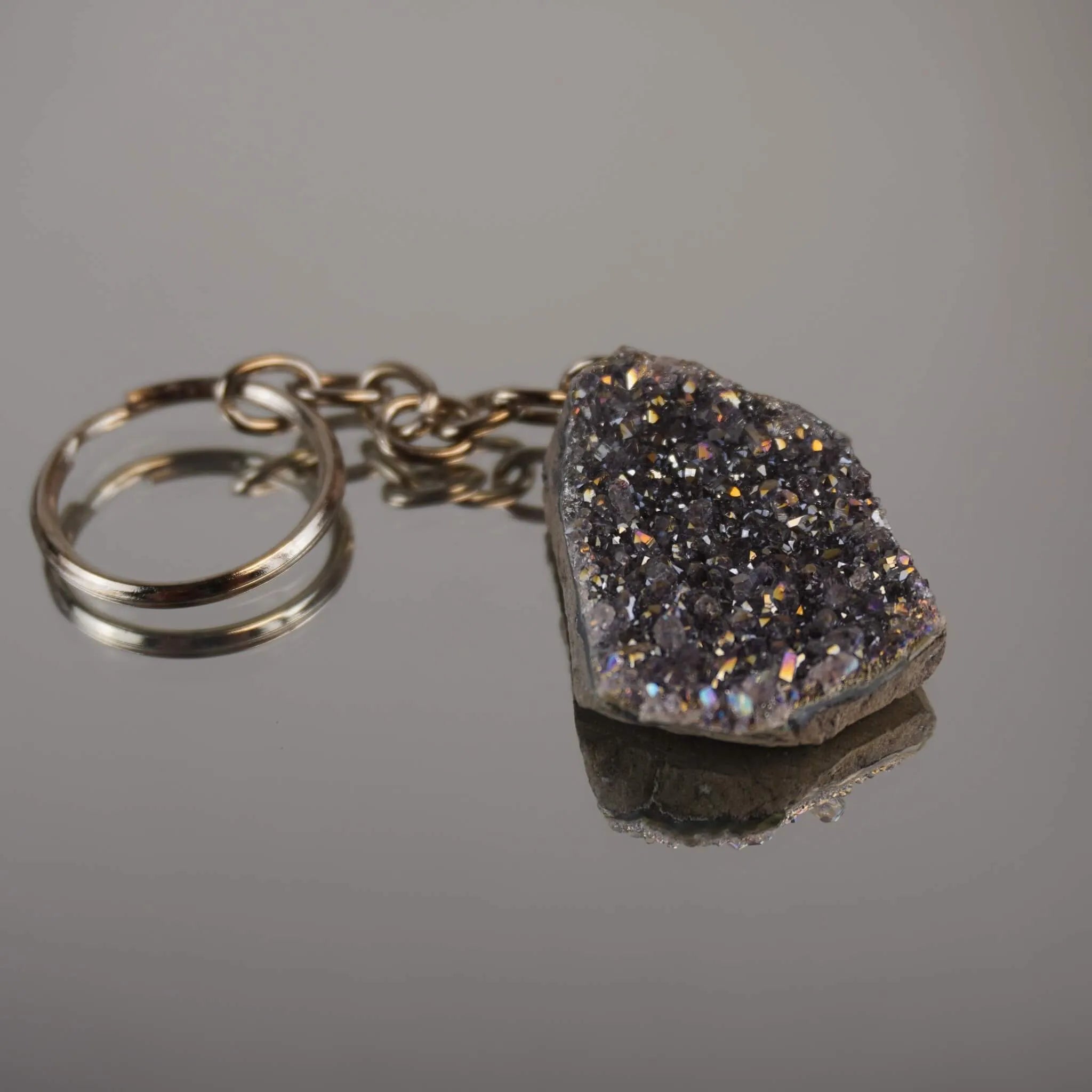 Lila Aqua Aura Druse Schlüsselanhänger mit Metallkette auf glänzender Fläche