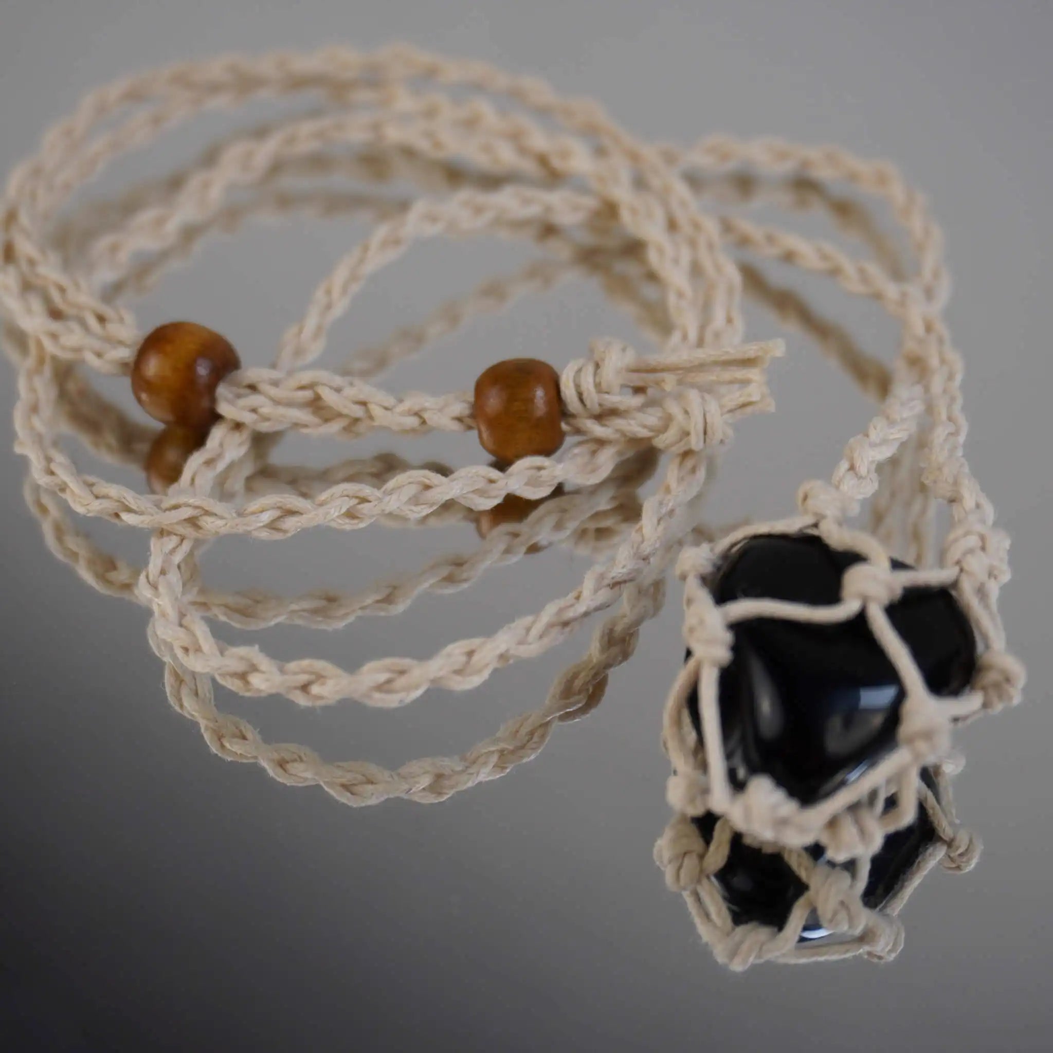 Makramee Halskette mit Edelsteinhalter auf spiegelnder Oberfläche