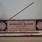 Satya Midnight Bloom Räucherstäbchen Packung mit angezündetem Räucherstäbchen im Vordergrund