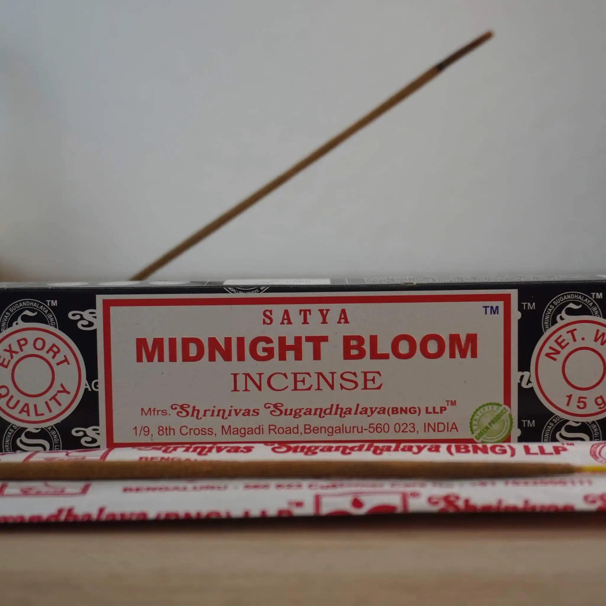Satya Midnight Bloom Räucherstäbchen Packung mit angezündetem Räucherstäbchen im Vordergrund