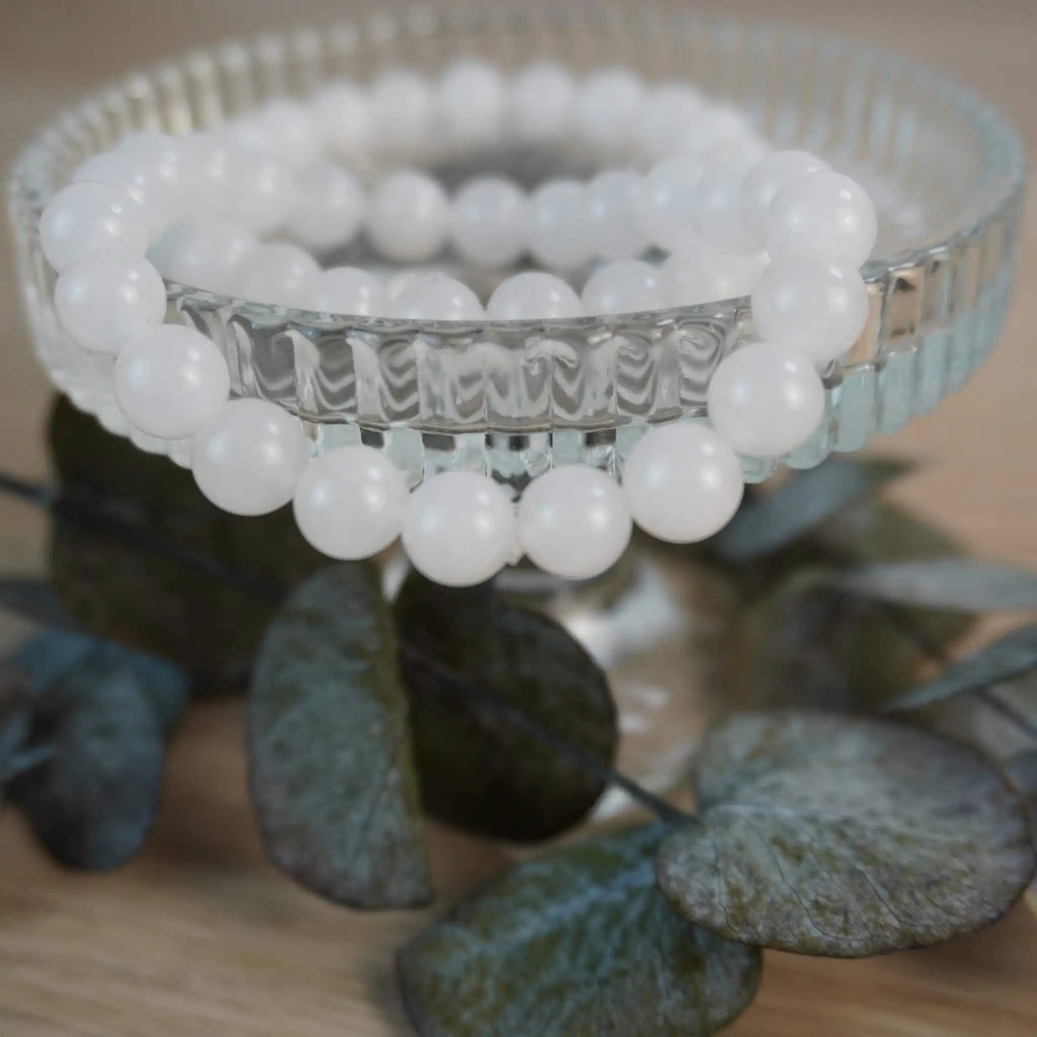 Mondstein Kugelarmband auf elegantem Glasdisplay mit Pflanzen-Dekoration