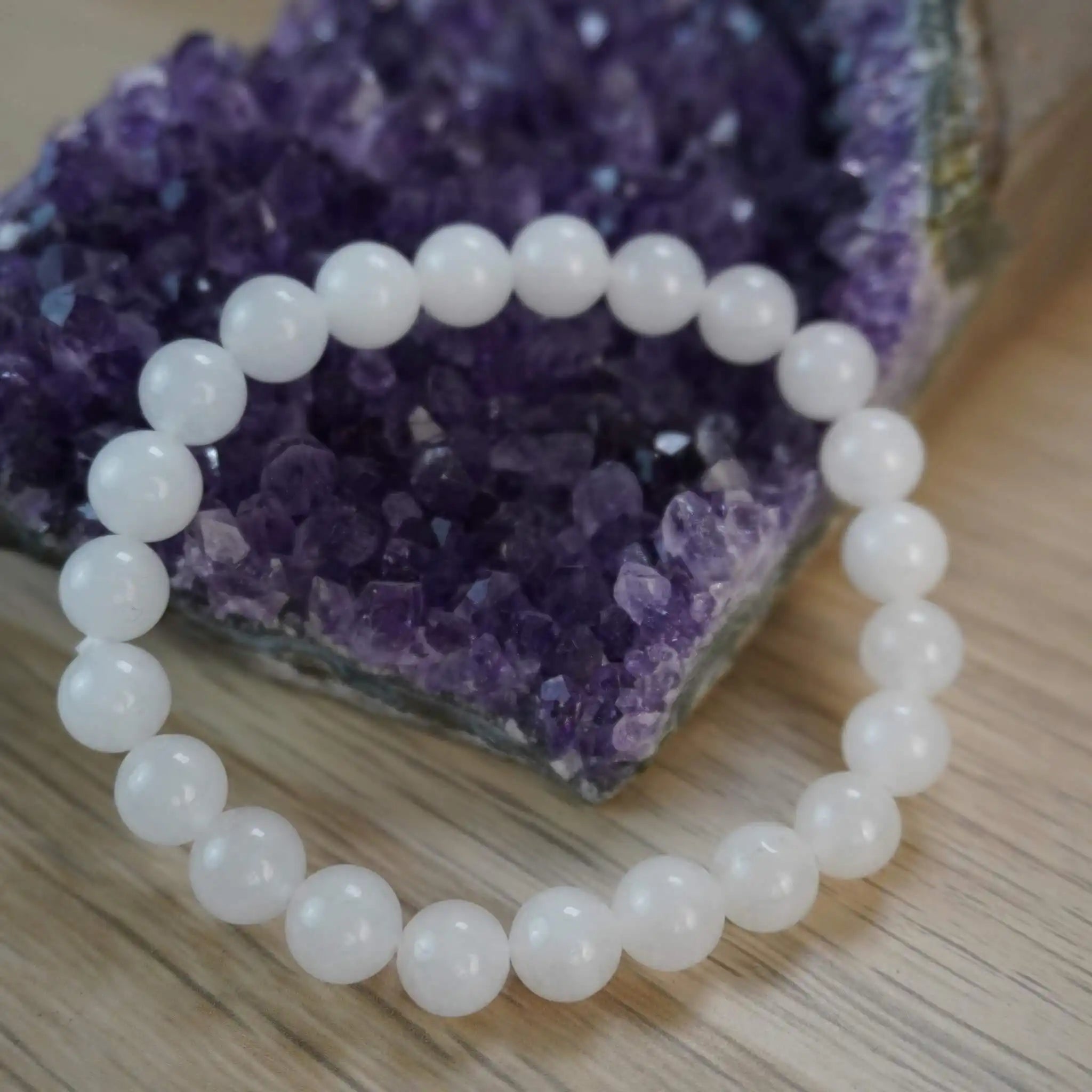 Mondstein Kugelarmband vor einem violetten Amethyst-Dekostein