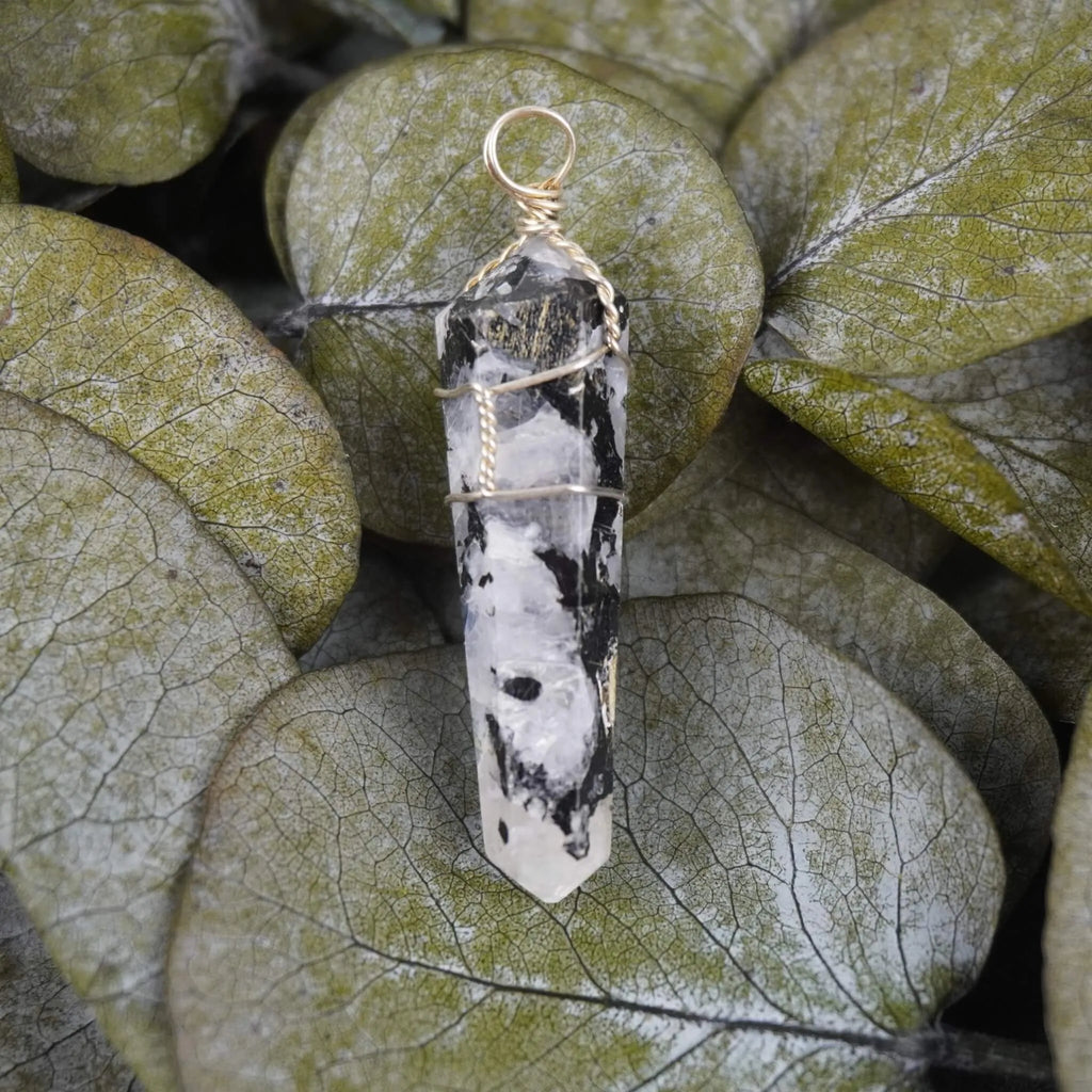 Mondstein Spitze Kettenanhänger dekoriert auf grünen Eukalyptusblättern