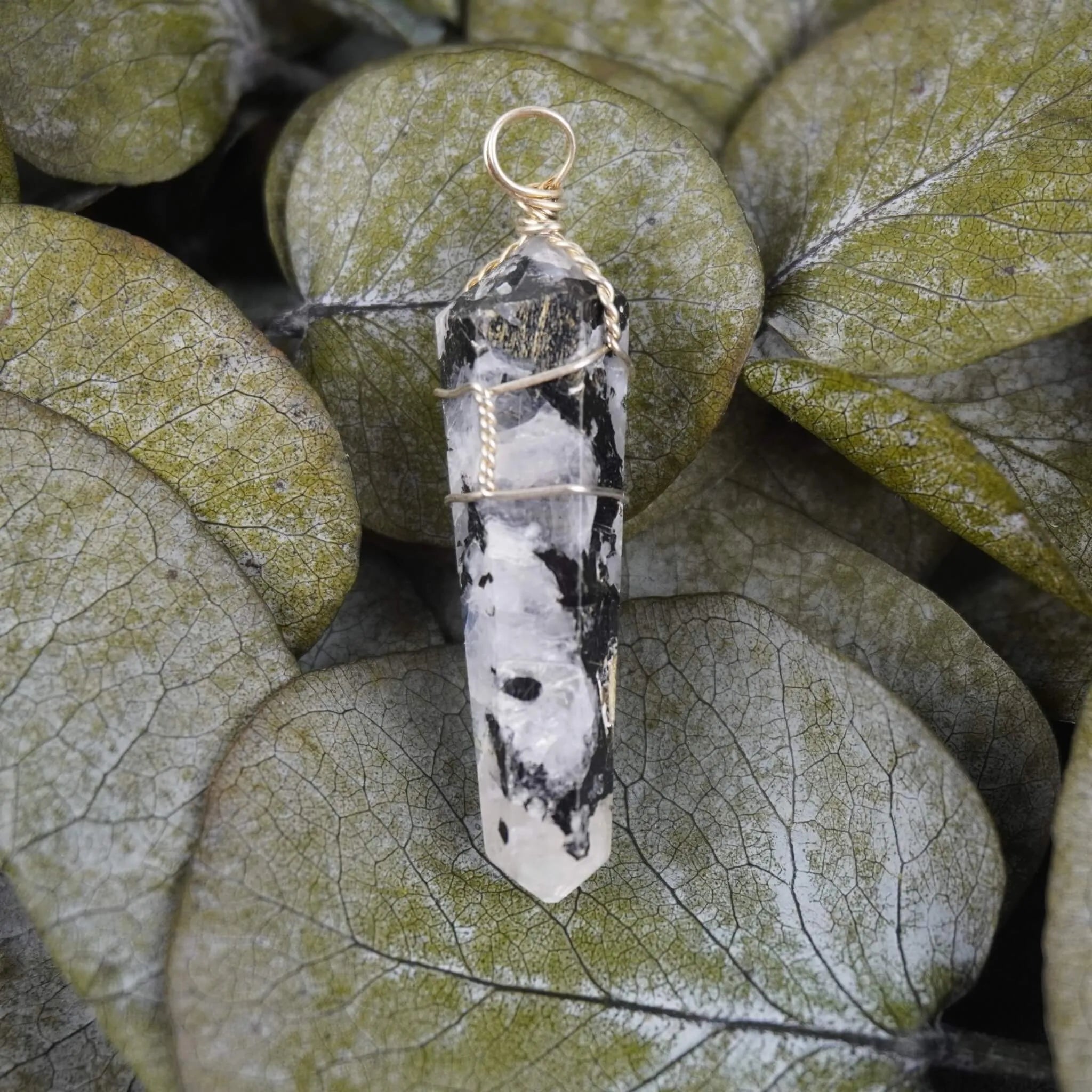 Mondstein Spitze Kettenanhänger dekoriert auf grünen Eukalyptusblättern