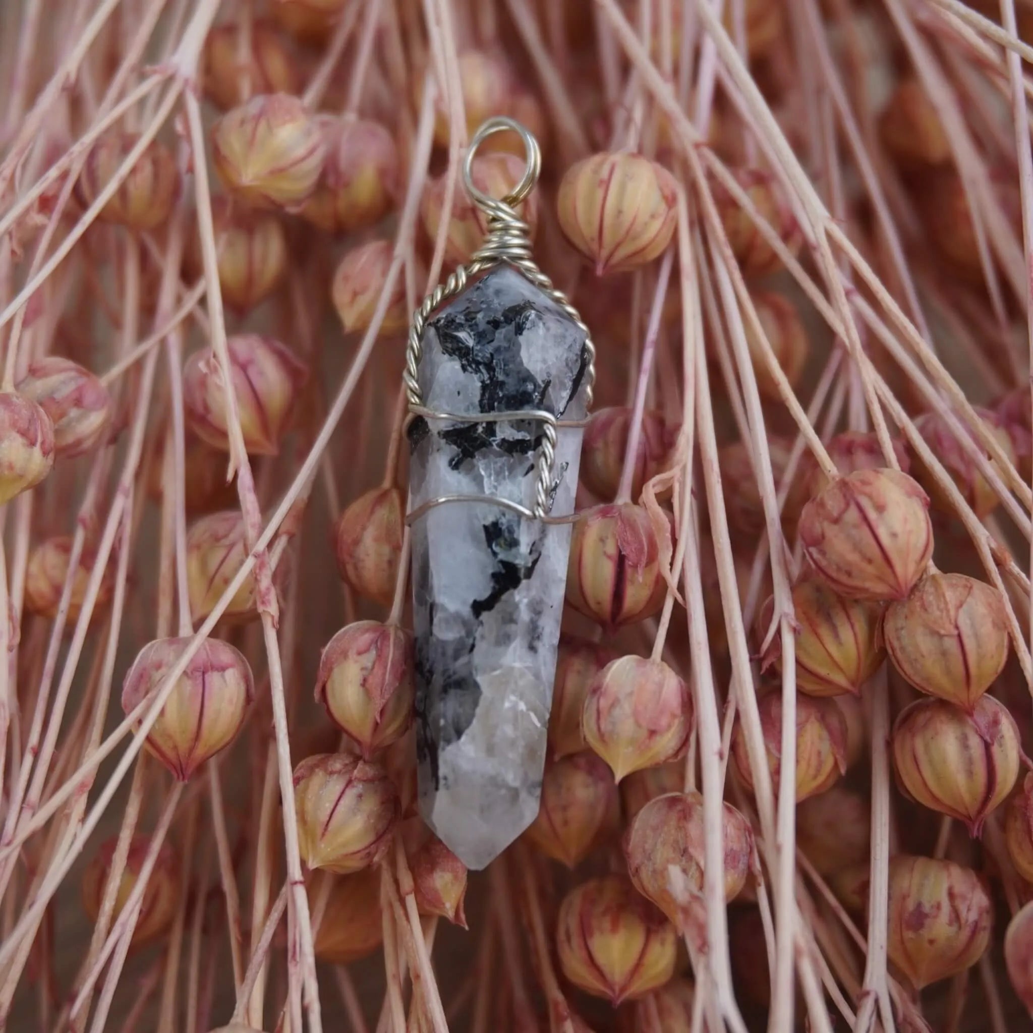 Mondstein Spitze Kettenanhänger mit Silberdraht vor rosa Trockenblumen