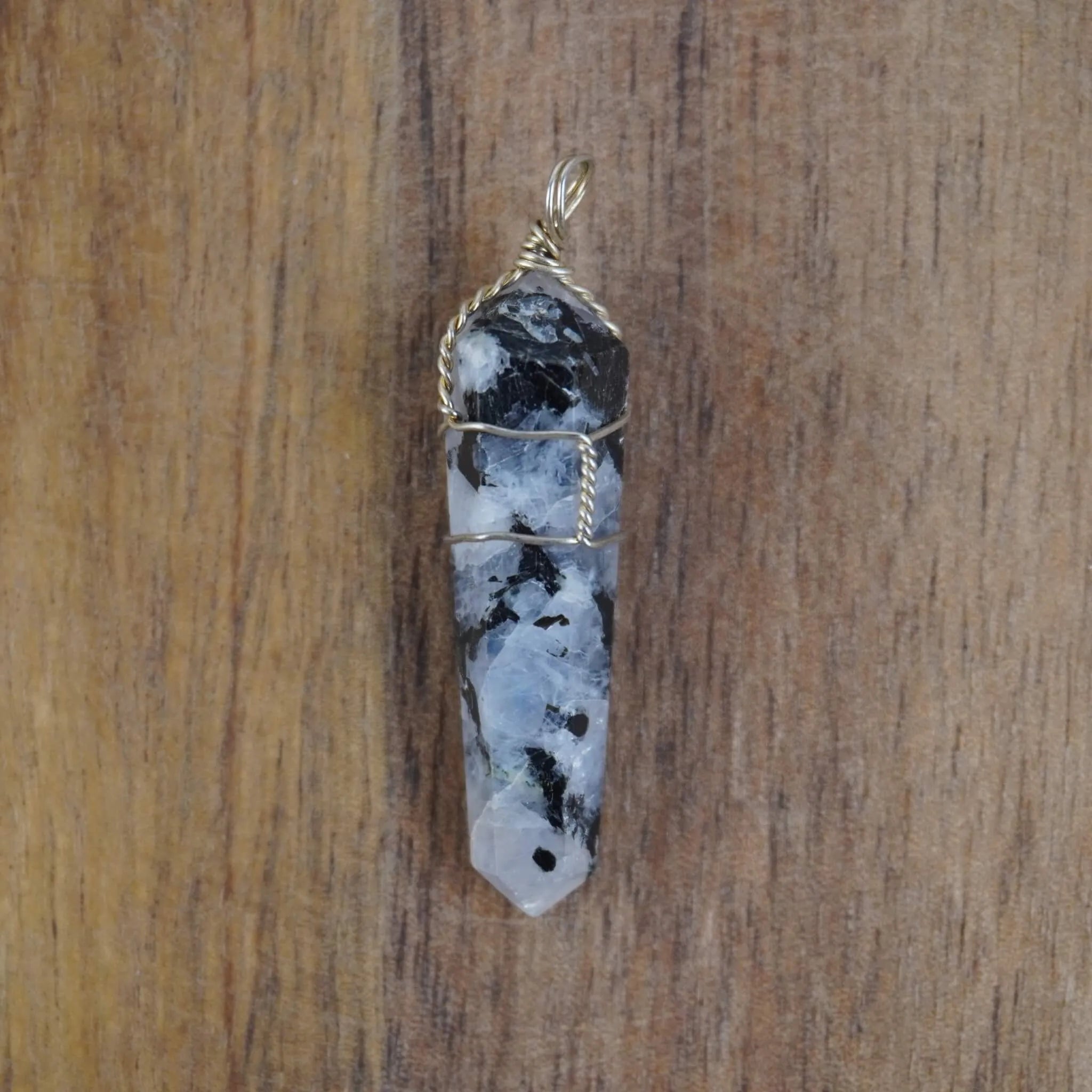 Mondstein Spitze Kettenanhänger mit Silberdraht auf Holzuntergrund