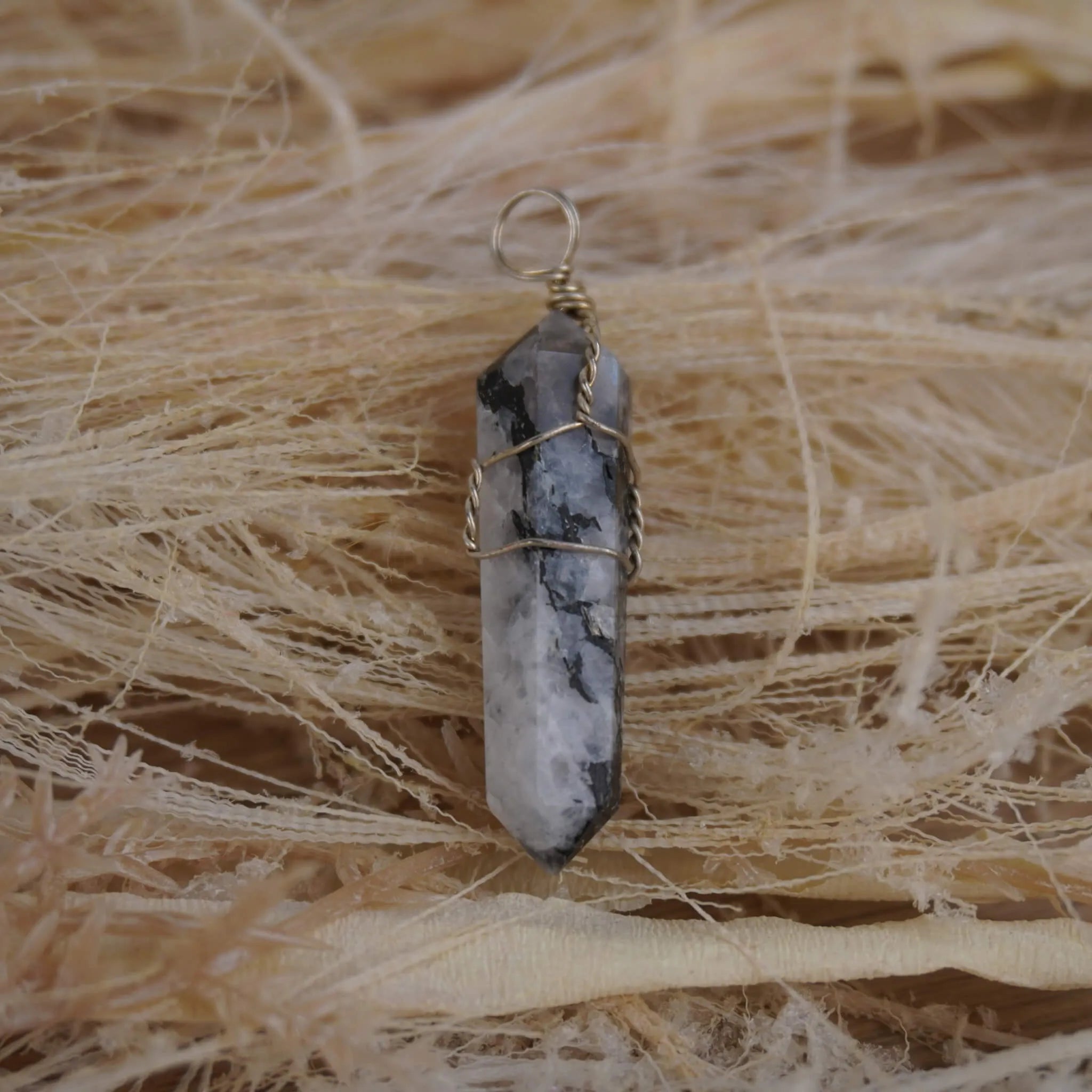 Mondstein Spitze Kettenanhänger mit Silberdraht auf hellen Naturfasern