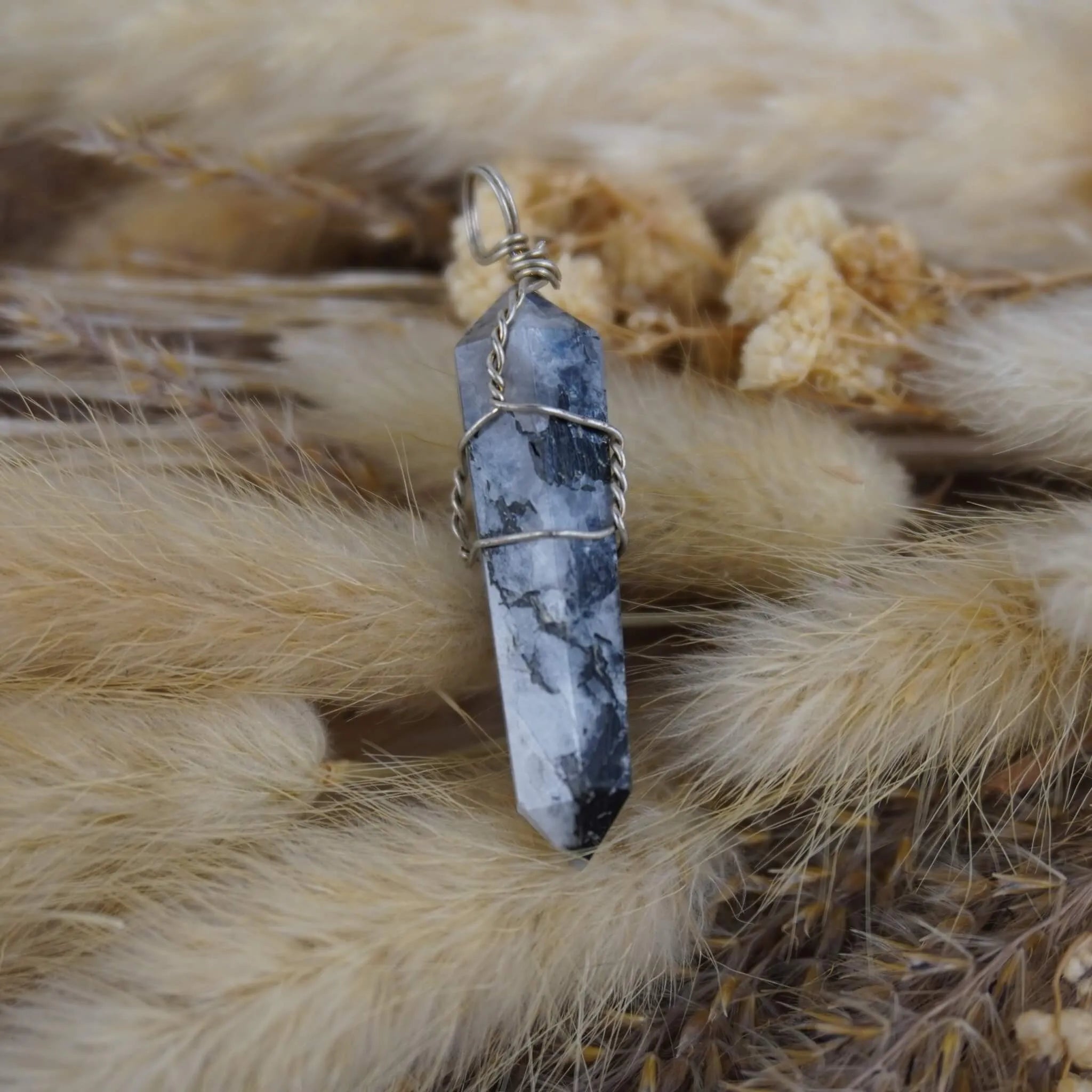 Mondstein Spitze Kettenanhänger auf beigen Trockenpflanzen arrangiert