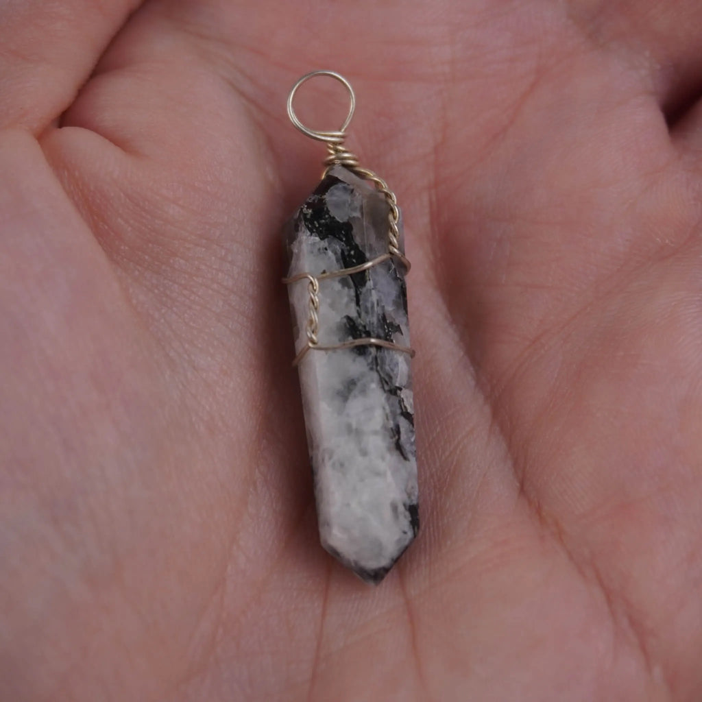 Mondstein Spitze Kettenanhänger mit Drahtfassung in einer Hand liegend
