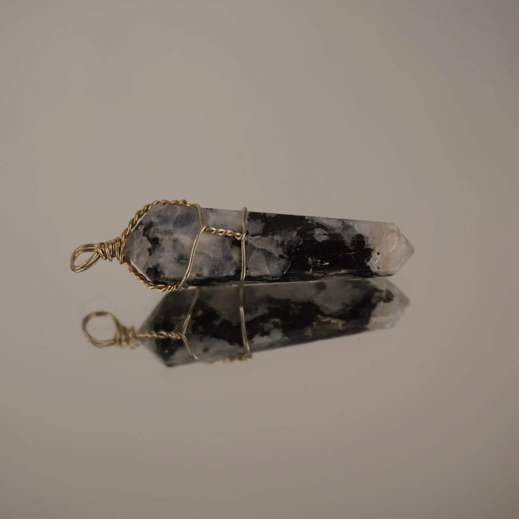 Liegender Mondstein Spitze Kettenanhänger mit Spiegelung auf glänzender Fläche