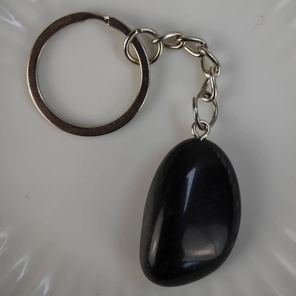 Obsidian Trommelstein Schlüsselanhänger in Nahaufnahme auf hellem Hintergrund