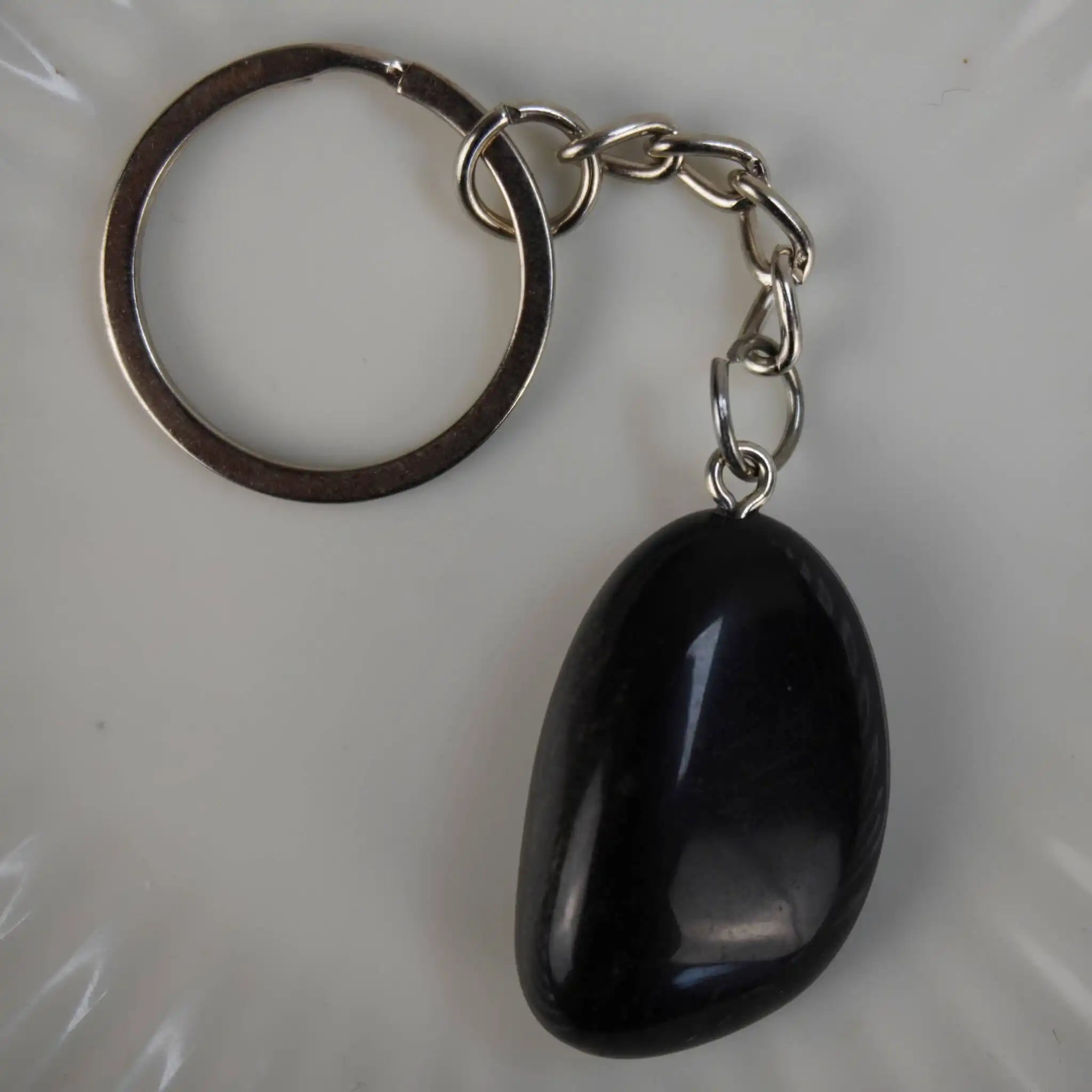 Obsidian Trommelstein Schlüsselanhänger in Nahaufnahme auf hellem Hintergrund