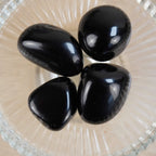 Vier Obsidian Trommelsteine in einer Glas-Schale von oben fotografiert