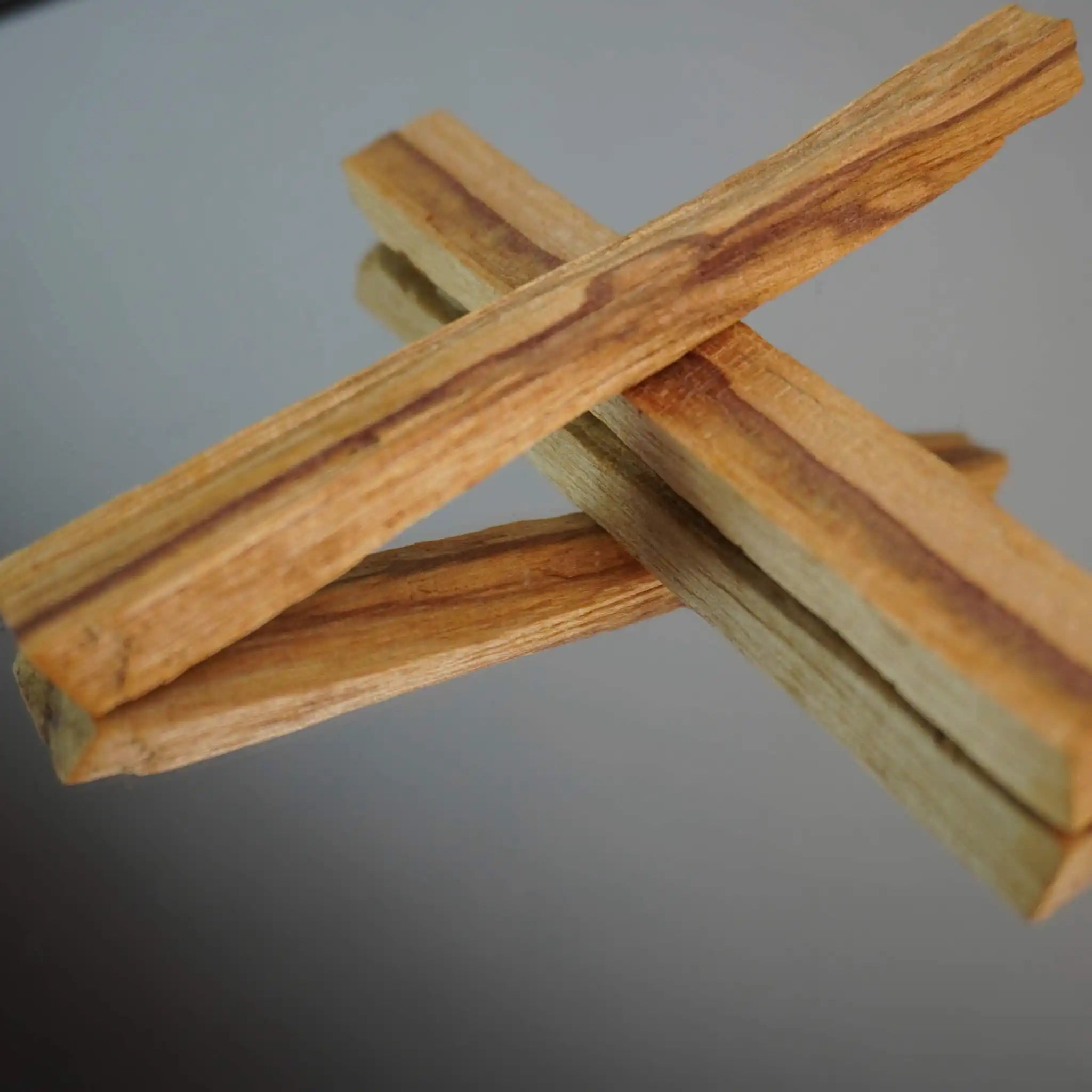Zwei Palo Santo Hölzer gekreuzt auf glänzendem Hintergrund