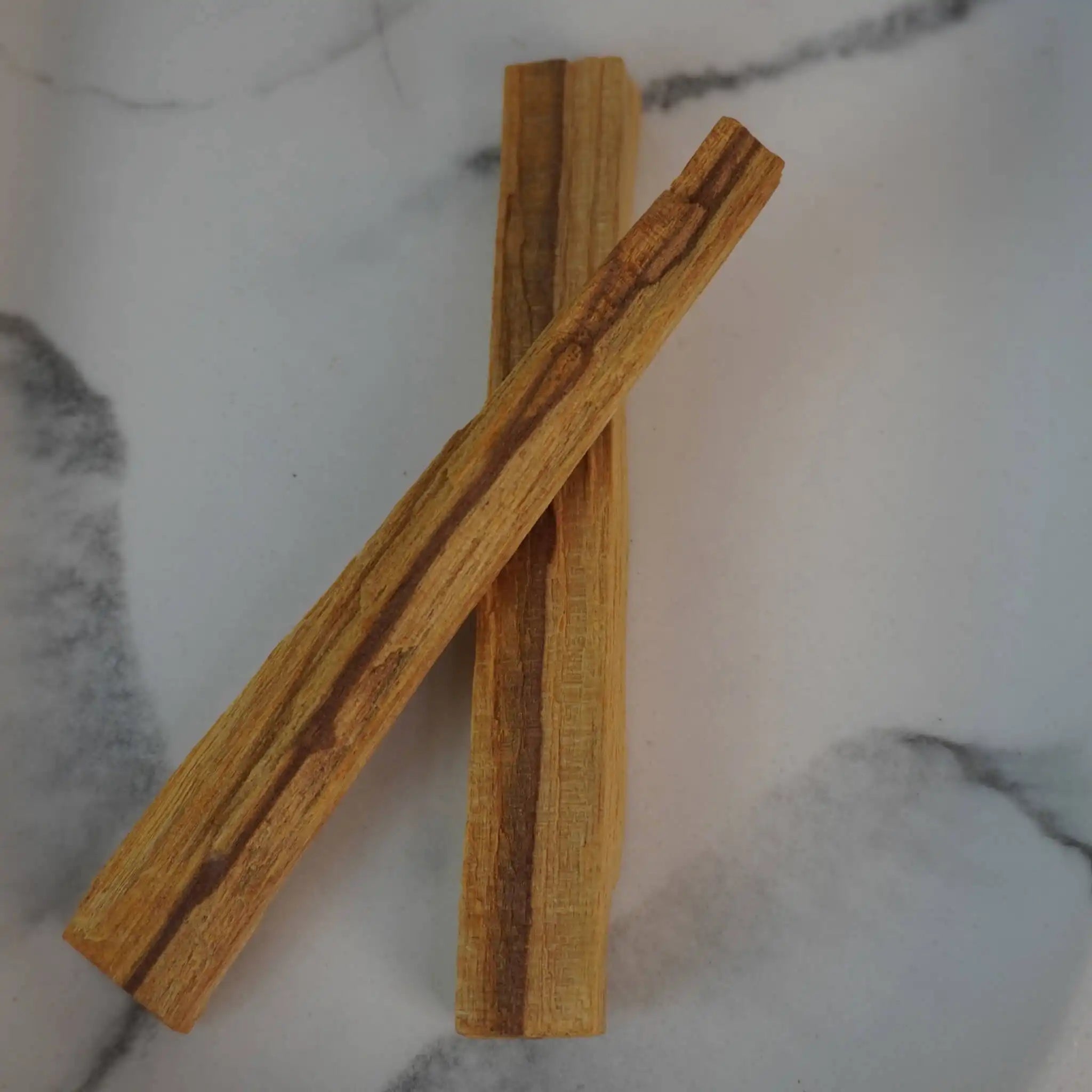 Zwei Palo Santo Hölzer auf hellem Marmorhintergrund