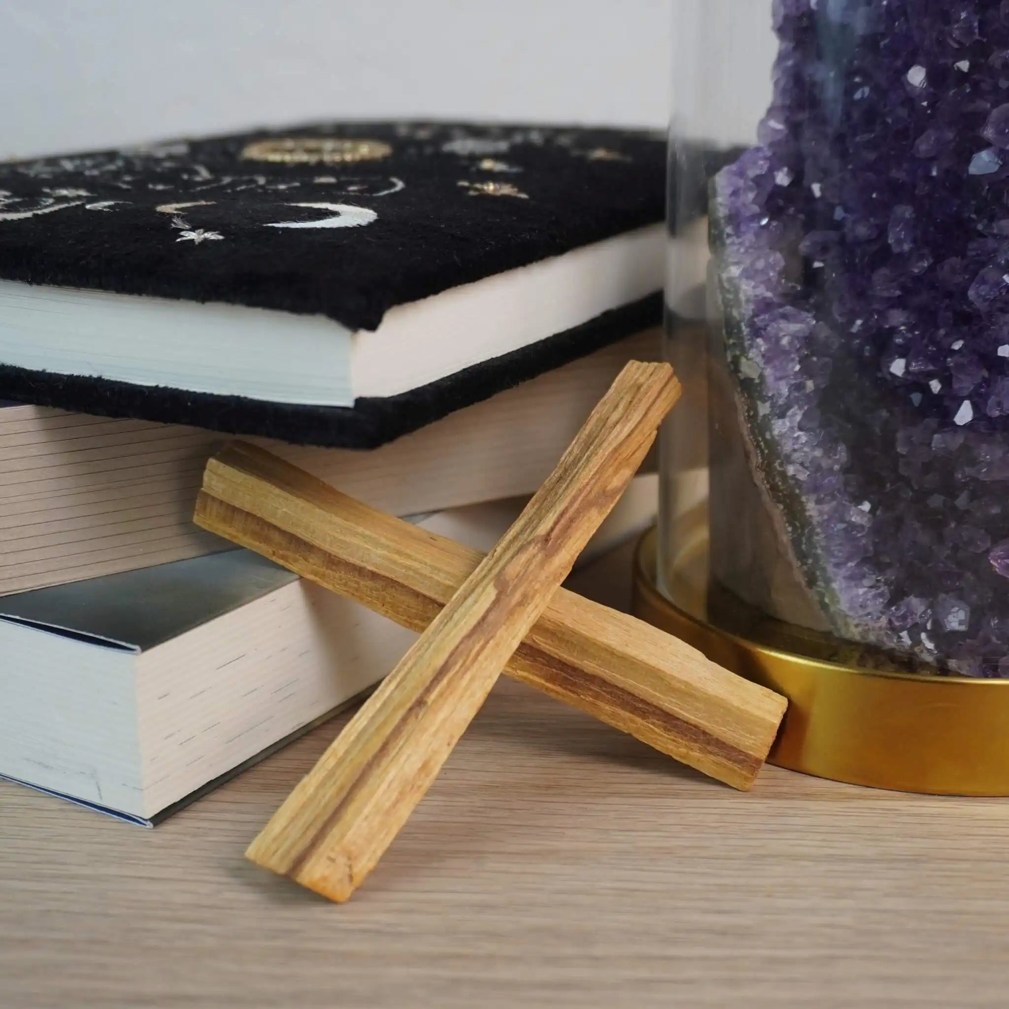 Palo Santo Hölzer neben einem Buch und einem Amethyst-Kristall