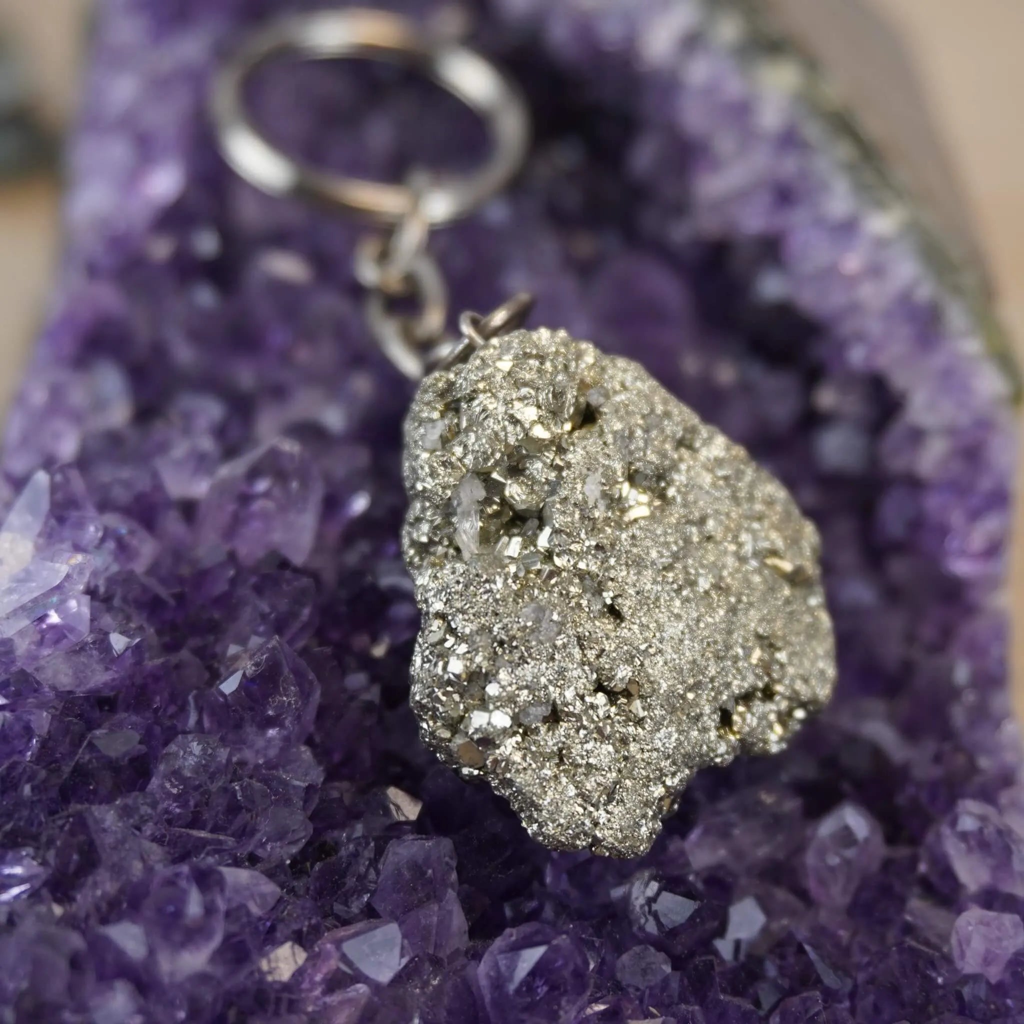 Pyrit Schlüsselanhänger präsentiert auf violetter Amethyst-Druse