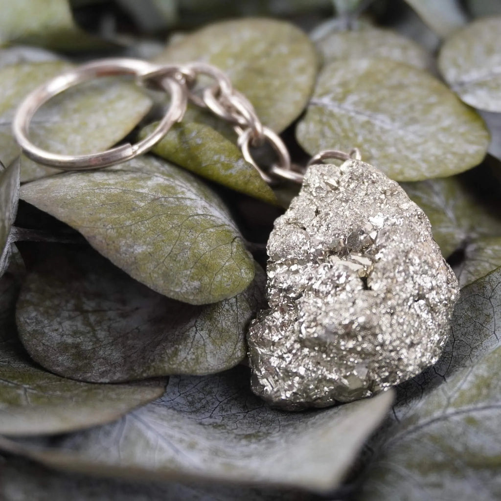 Pyrit Schlüsselanhänger arrangiert auf grünen Eukalyptusblättern