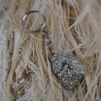 Pyrit Schlüsselanhänger auf hellen Naturfasern arrangiert