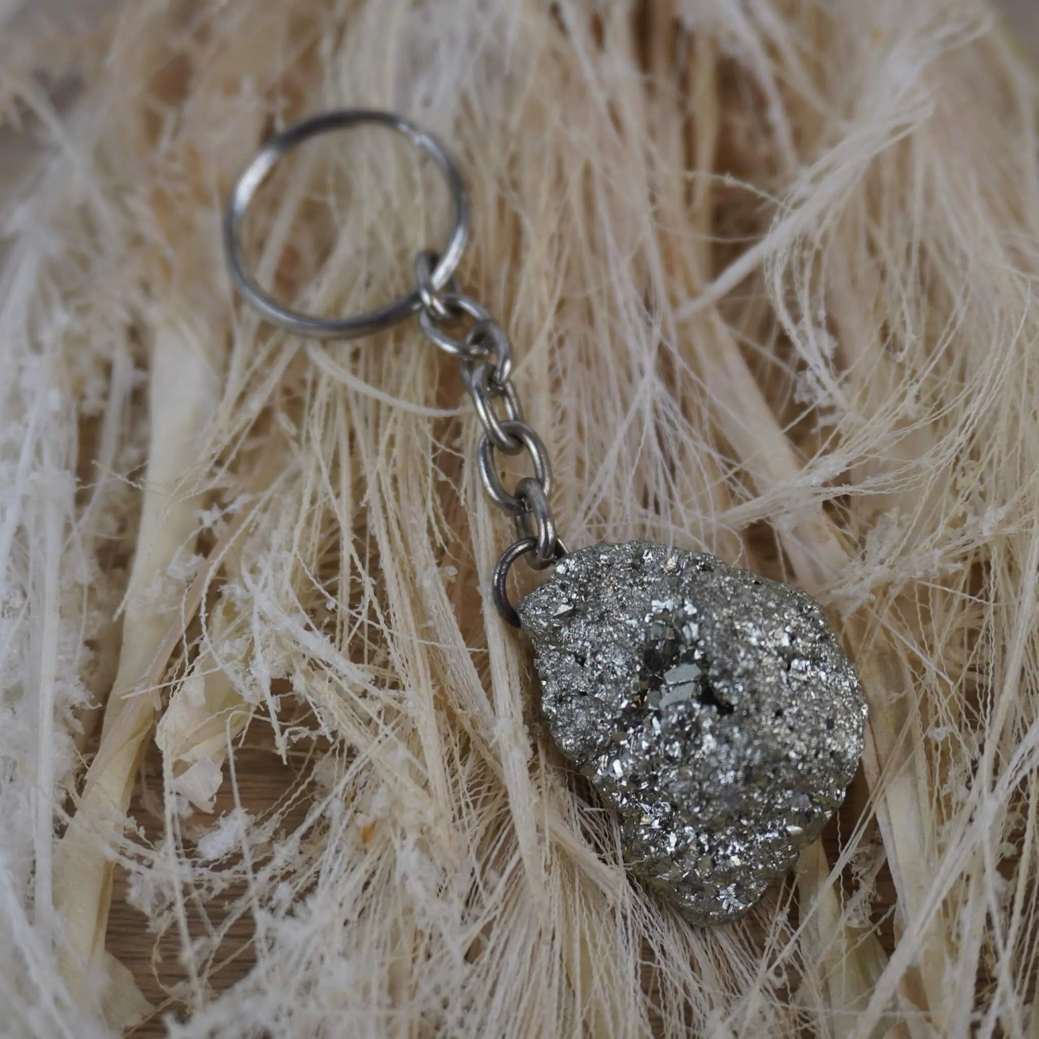 Pyrit Schlüsselanhänger auf hellen Naturfasern arrangiert