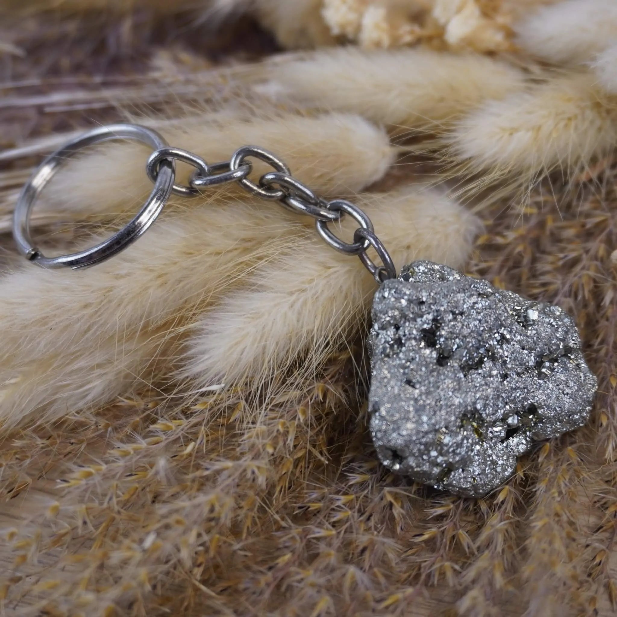 Pyrit Schlüsselanhänger auf beigen flauschigen Trockenpflanzen dekoriert