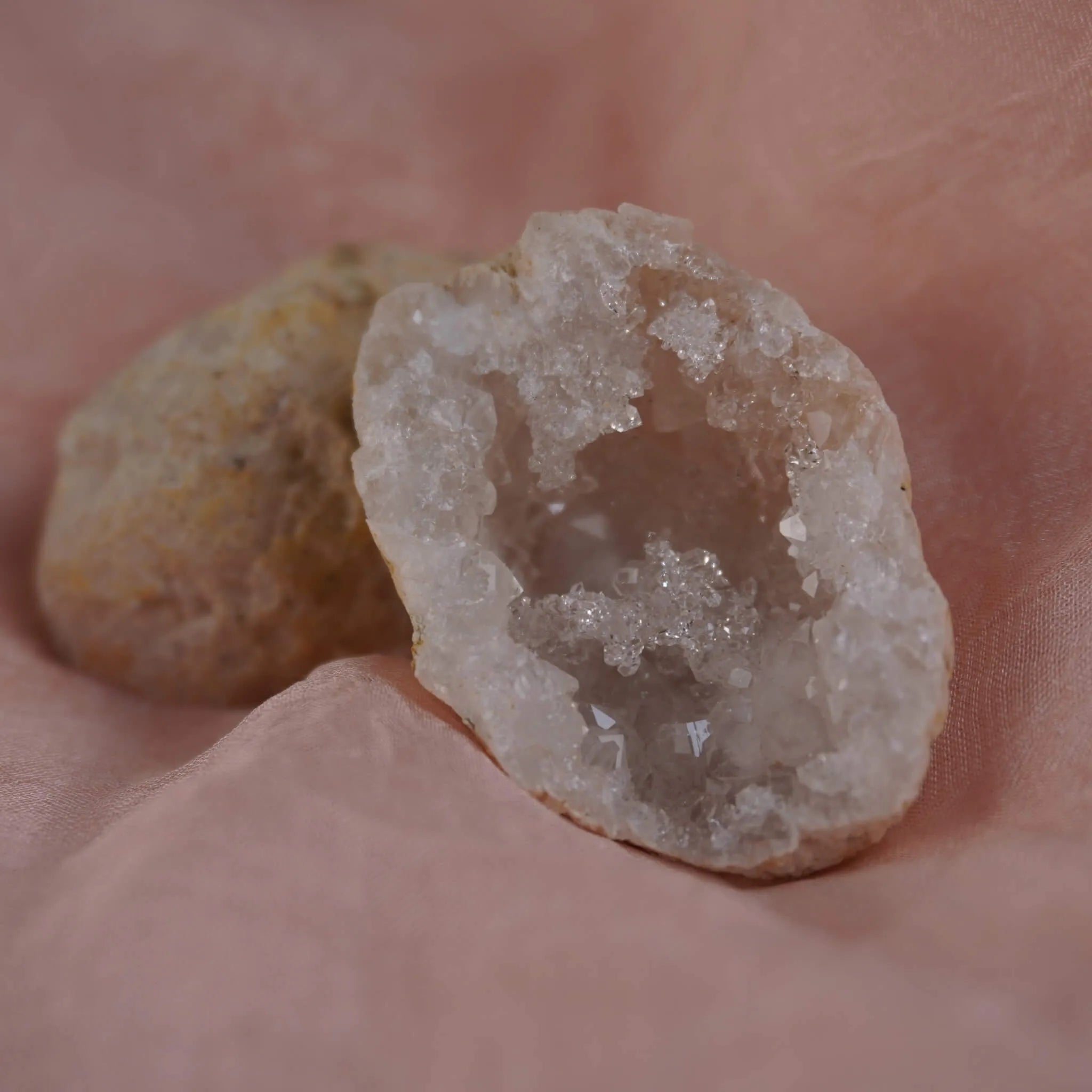 Funkelnde Quarz Geode mit Kristallhöhle auf rosafarbenem Stoff