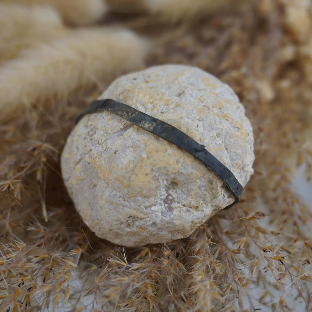 Geschlossene helle Quarz Geode mit Gummiband auf beigen Ziergräsern arrangiert