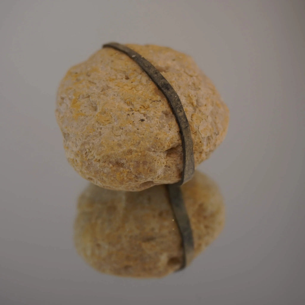 Geschlossene Quarz Geode mit umlaufendem Gummiband auf spiegelnder Fläche