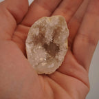 Geöffnete Quarz Geode mit funkelnden Kristallen in einer Hand gehalten