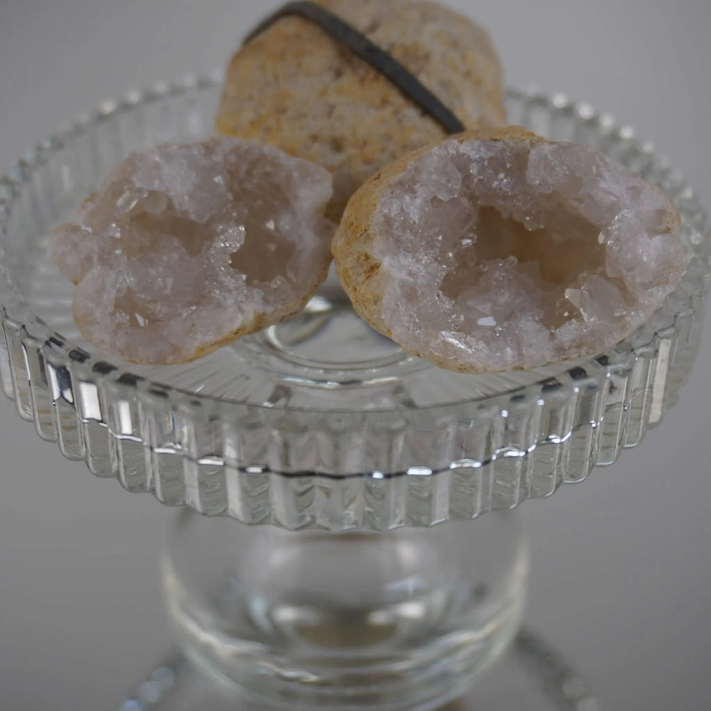 Aufgebrochene Quarz Geoden mit funkelnden Kristallen auf einem erhöhten Glaskelch