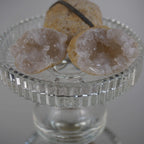 Aufgebrochene Quarz Geoden mit funkelnden Kristallen auf einem erhöhten Glaskelch