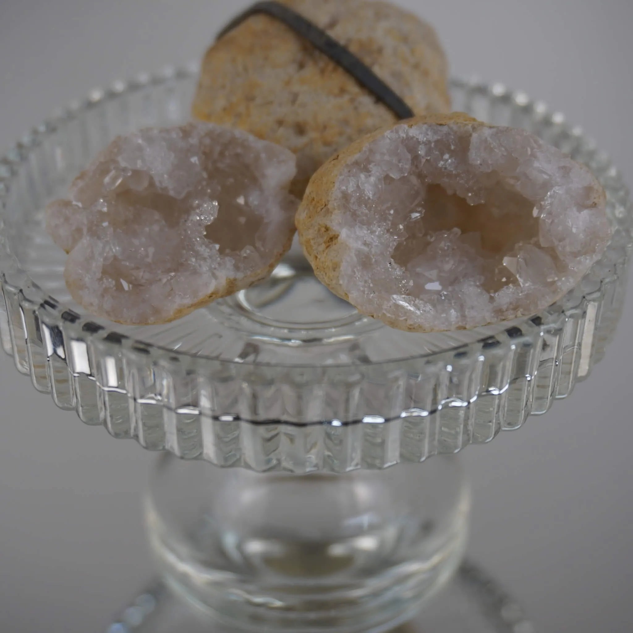 Aufgebrochene Quarz Geoden mit funkelnden Kristallen auf einem erhöhten Glaskelch