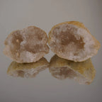 Zwei aufgebrochene Quarz Geoden mit Spiegelung auf glänzender Unterlage