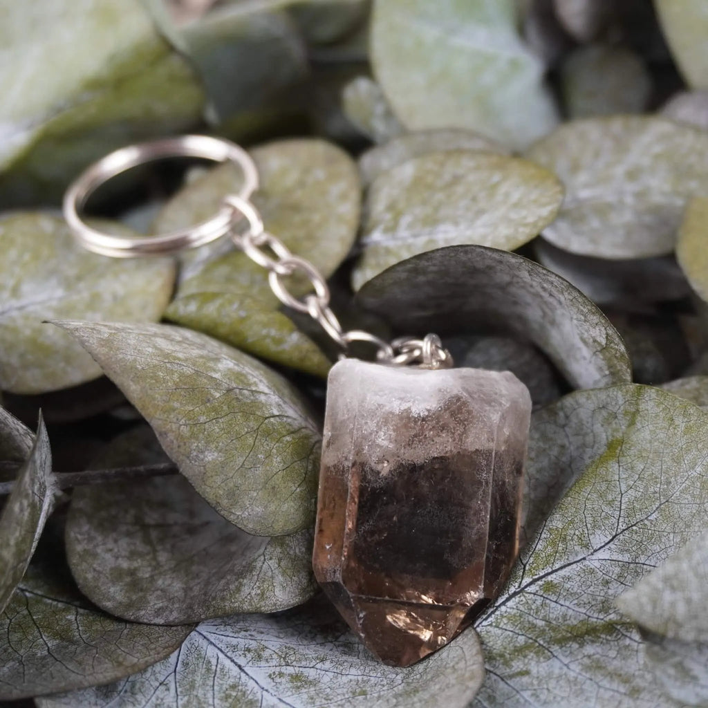 Rauchquarz Spitze Schlüsselanhänger arrangiert auf grünen Eukalyptusblättern