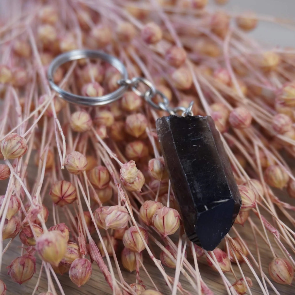 Rauchquarz Spitze Schlüsselanhänger präsentiert auf rosa getrockneten Gräsern