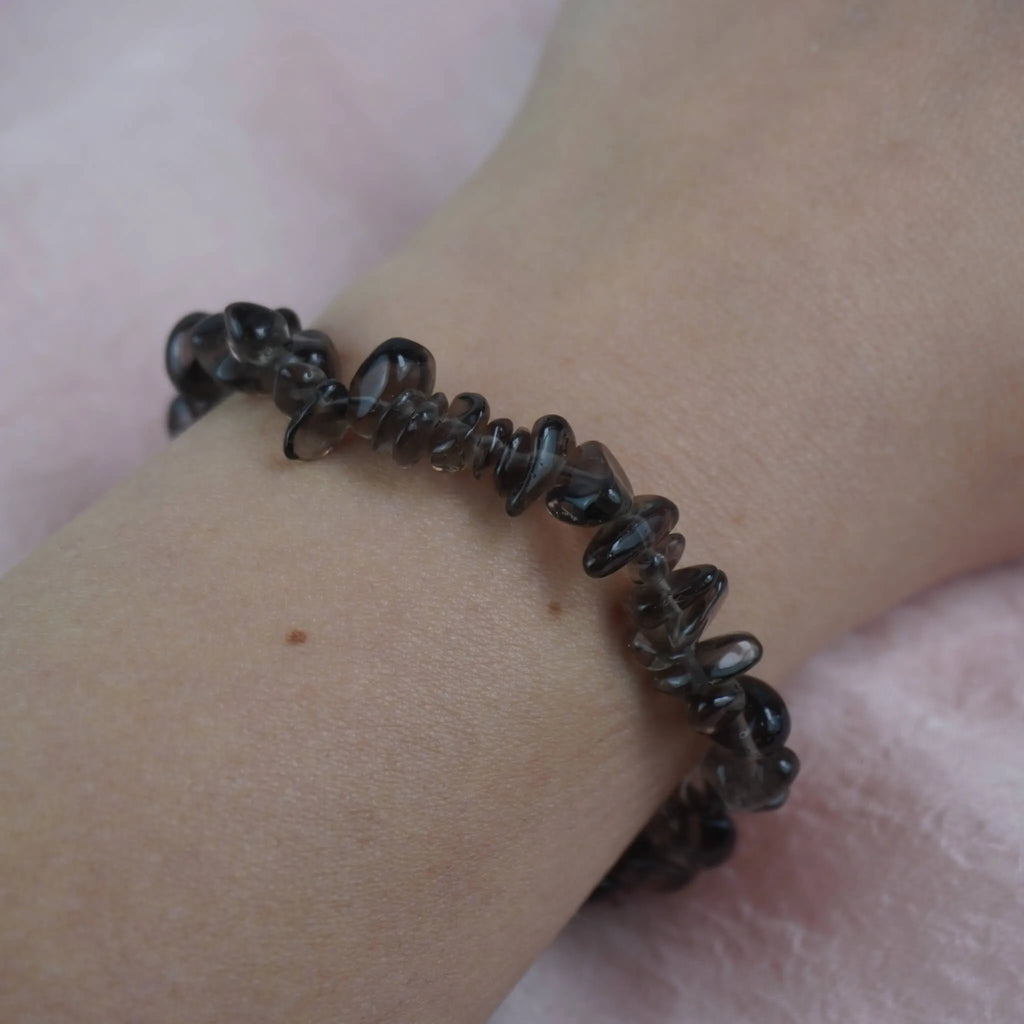 Rauchquarz‑Splitterarmband am Handgelenk auf rosa Untergrund
