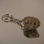 Roher Pyrit Schlüsselanhänger auf spiegelnder Fläche mit Reflexion