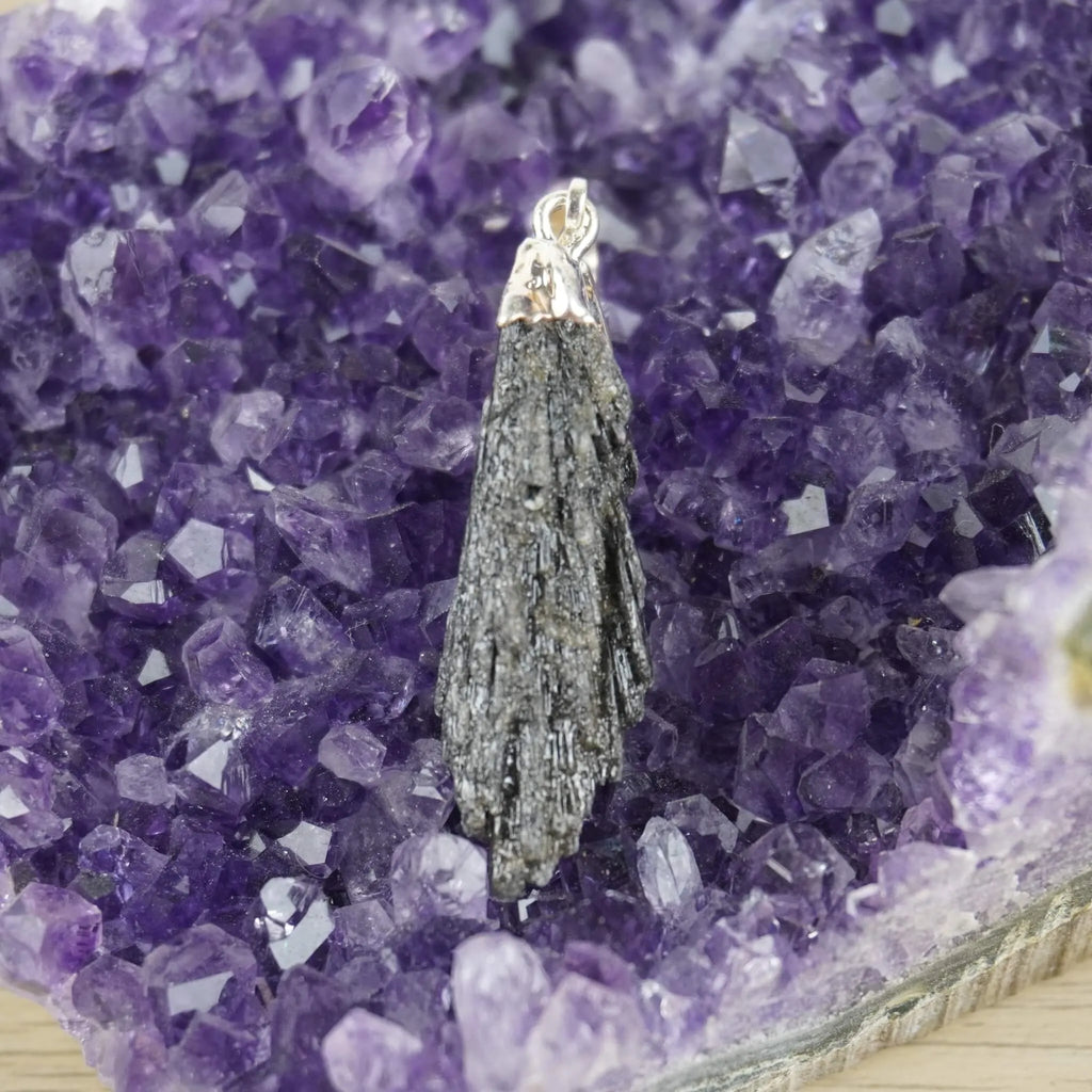 Roher schwarzer Kyanit Kettenanhänger mit silberner Metallfassung auf violetter Amethyst-Druse