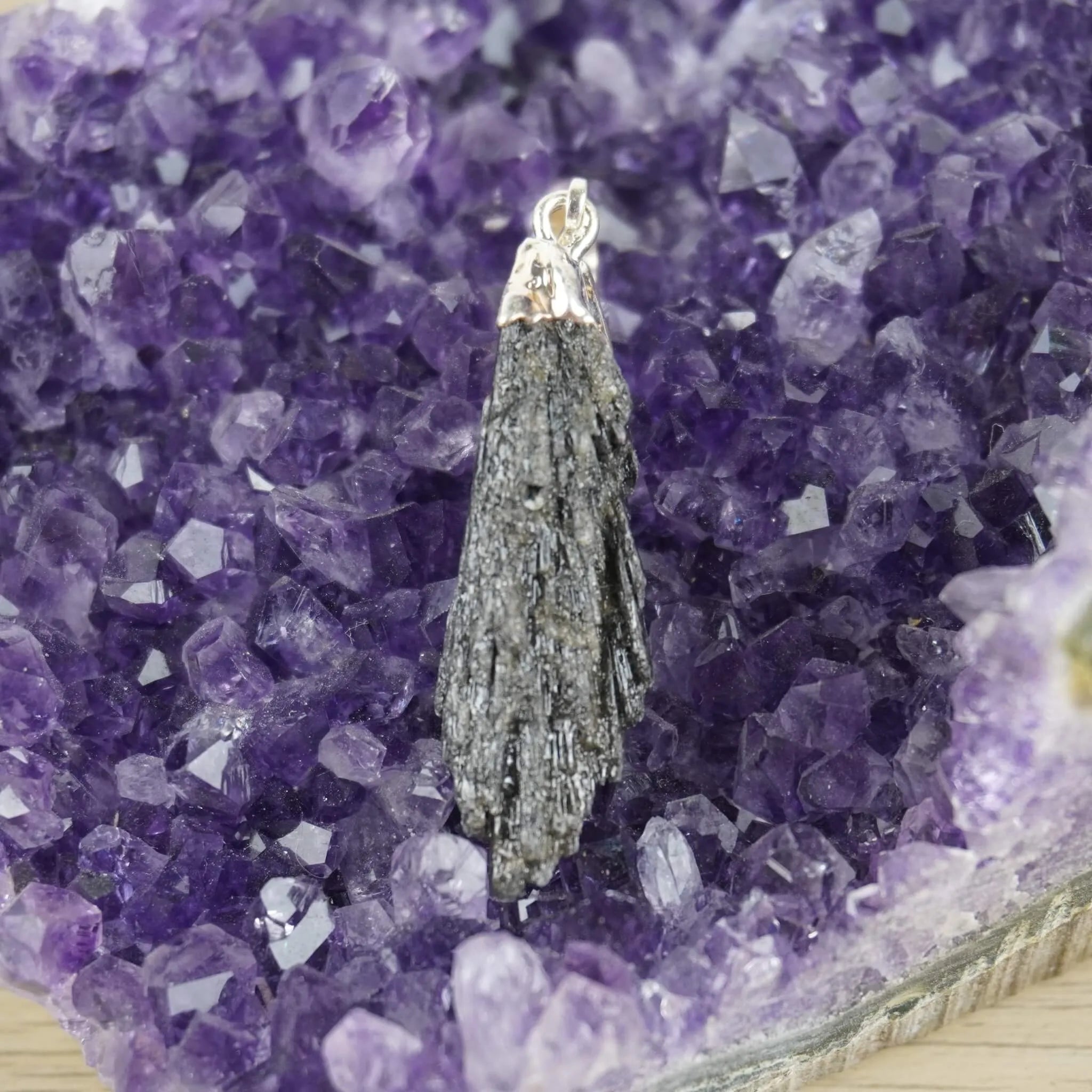 Roher schwarzer Kyanit Kettenanhänger mit silberner Metallfassung auf violetter Amethyst-Druse