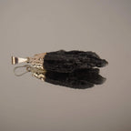 Liegender roher schwarzer Kyanit Kettenanhänger mit Spiegelung auf glänzender Fläche