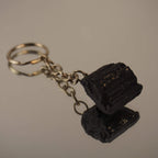 Roher schwarzer Turmalin Schlüsselanhänger auf spiegelnder Fläche mit Reflexion