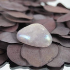 Rosa Angel Aura Trommelstein mit zartem Regenbogenschimmer auf lila Trockenblättern