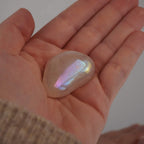 Rosa Angel Aura Trommelstein mit irisierendem Schimmer in einer geöffneten Hand