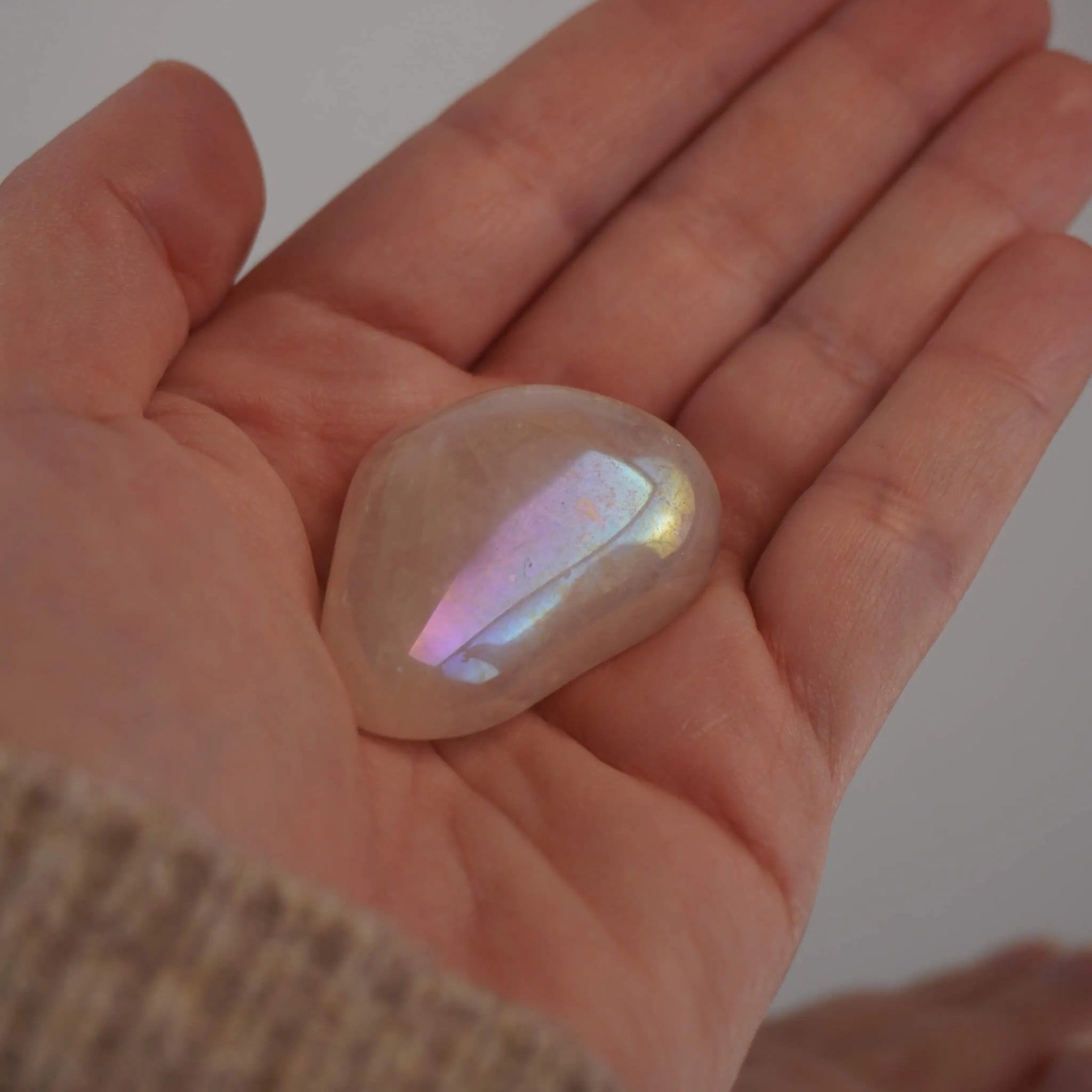 Rosa Angel Aura Trommelstein mit irisierendem Schimmer in einer geöffneten Hand