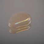 Einzelner rosa Angel Aura Trommelstein mit goldenem und violettem Schimmer auf Spiegelglas