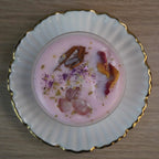 Duftkerze mit Rosenduft und Rosenquarz, auf weißen Porzellanteller mit goldener Verzierung präsentiert