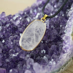 Halskette mit Rosenquarz-Anhänger auf violetten Amethyst-Kristallen