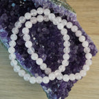 Rosenquarz Kugelarmband dekoriert auf einem Amethyst Stein