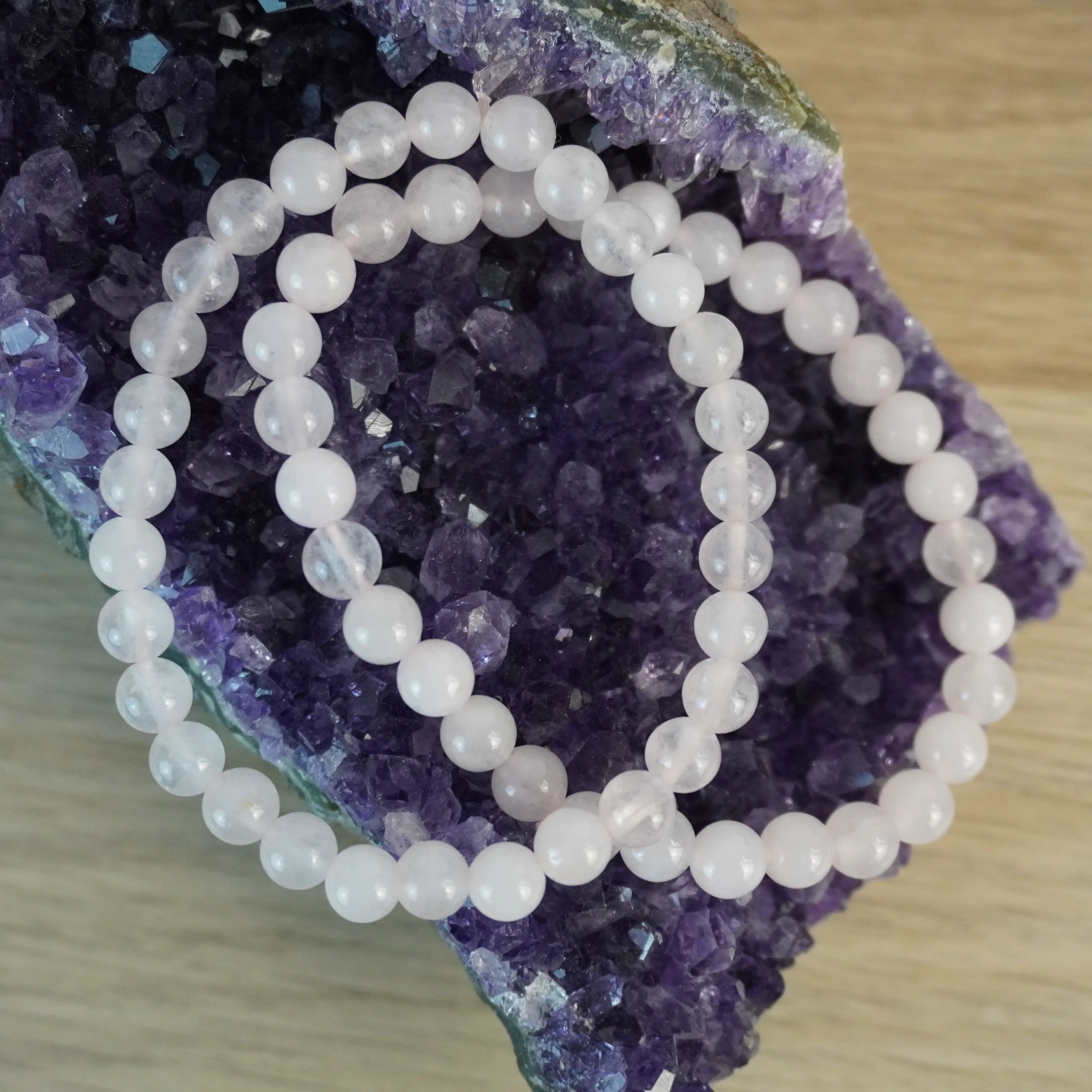 Rosenquarz Kugelarmband dekoriert auf einem Amethyst Stein
