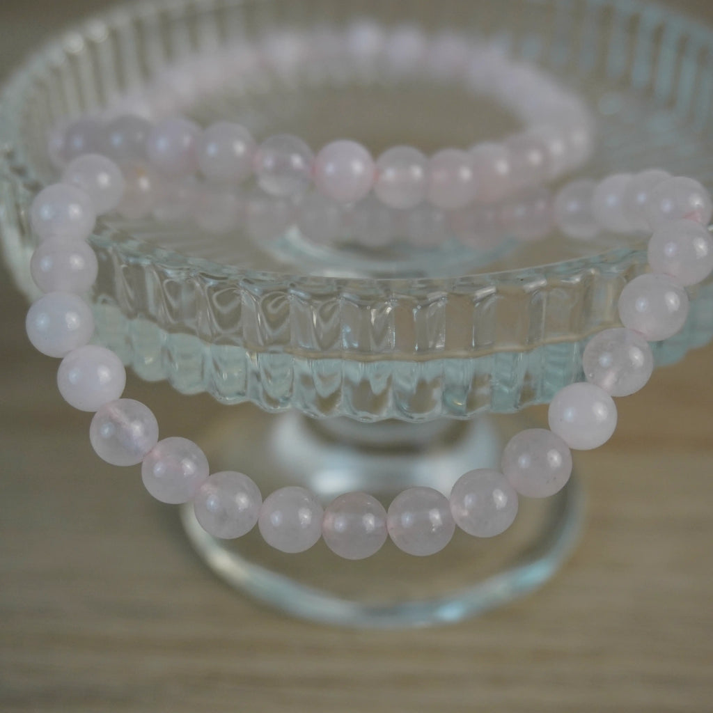 Rosenquarz Kugelarmband dekorativ auf Glasständer arrangiert